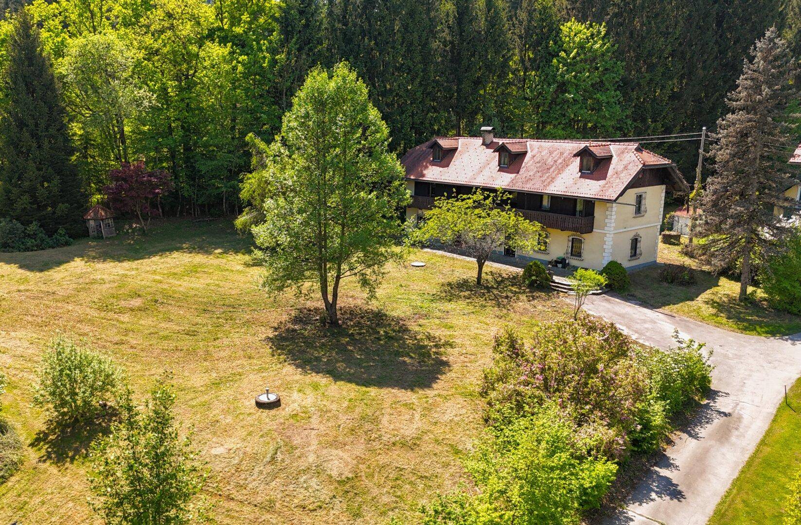 Luftaufnahme des Landhauses mit weitläufigem Grundstück und angrenzendem Waldgebiet.