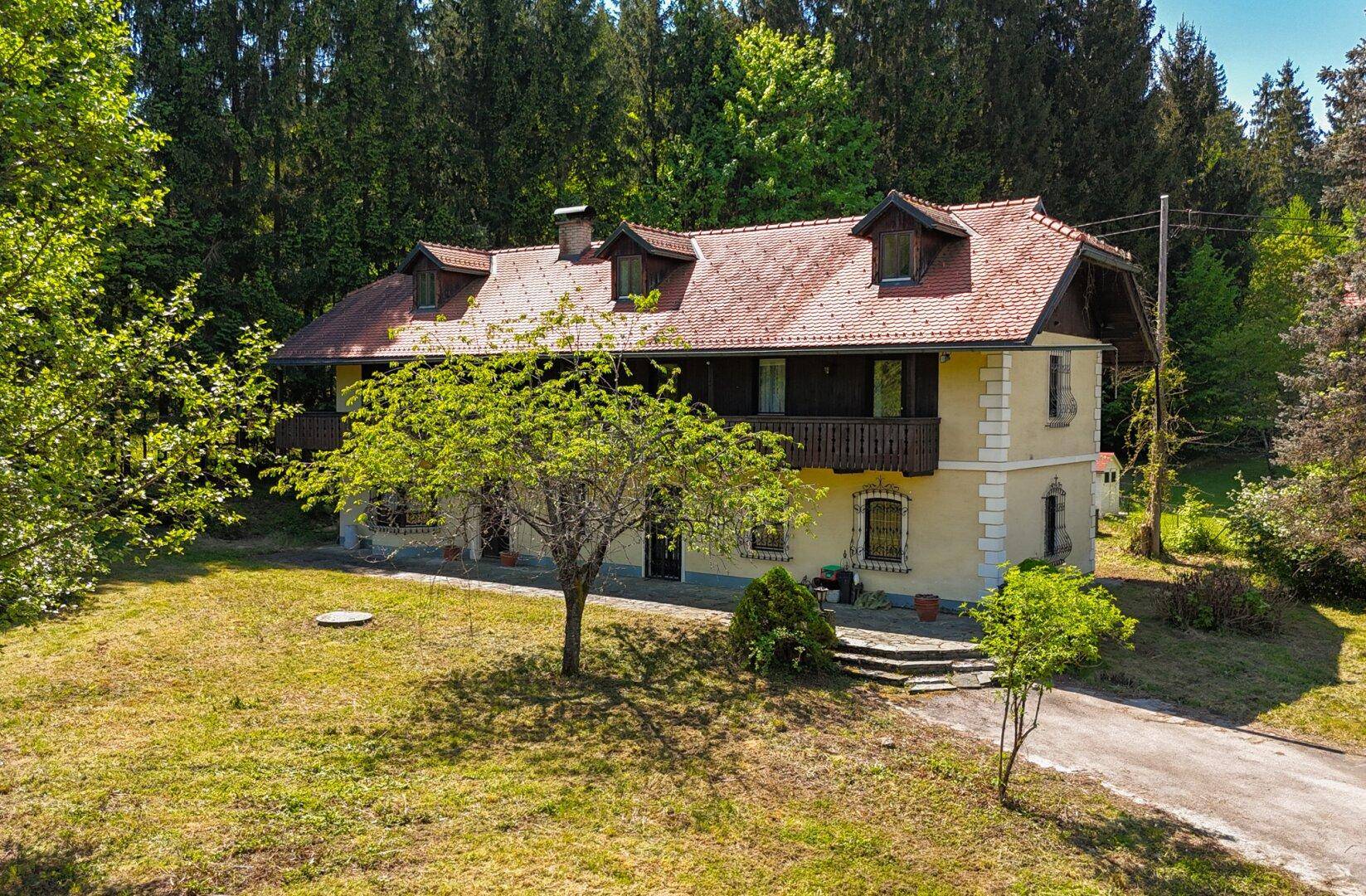 Charmantes Landhaus mit traditioneller Architektur, Holzbalkonen und weitläufigem Grundstück.