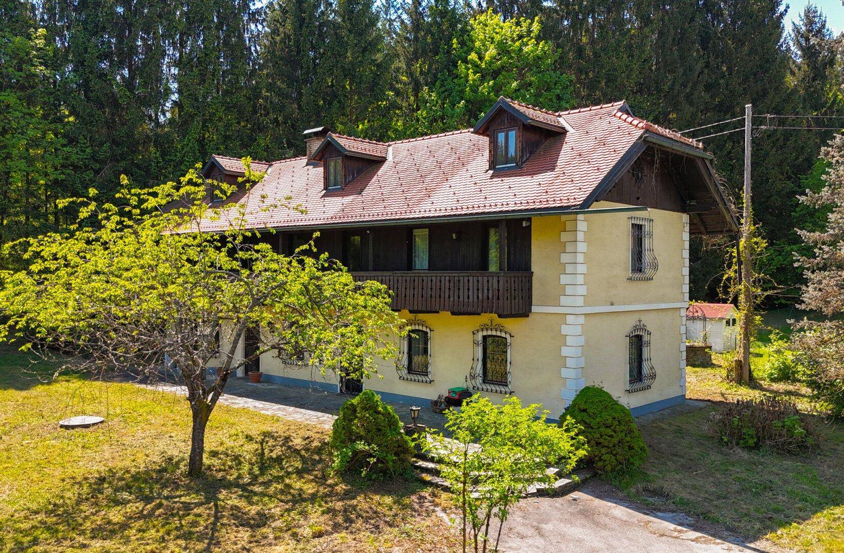 Idyllisches Landhaus mit traditionellen Holzbalkonen und gepflegtem Vorgarten in sonniger Lage.