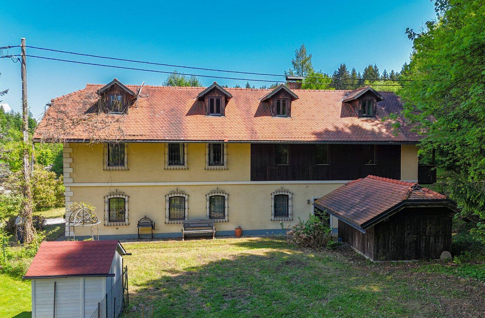 Rückseite des Landhauses mit Nebengebäuden und Blick auf den Gartenbereich.