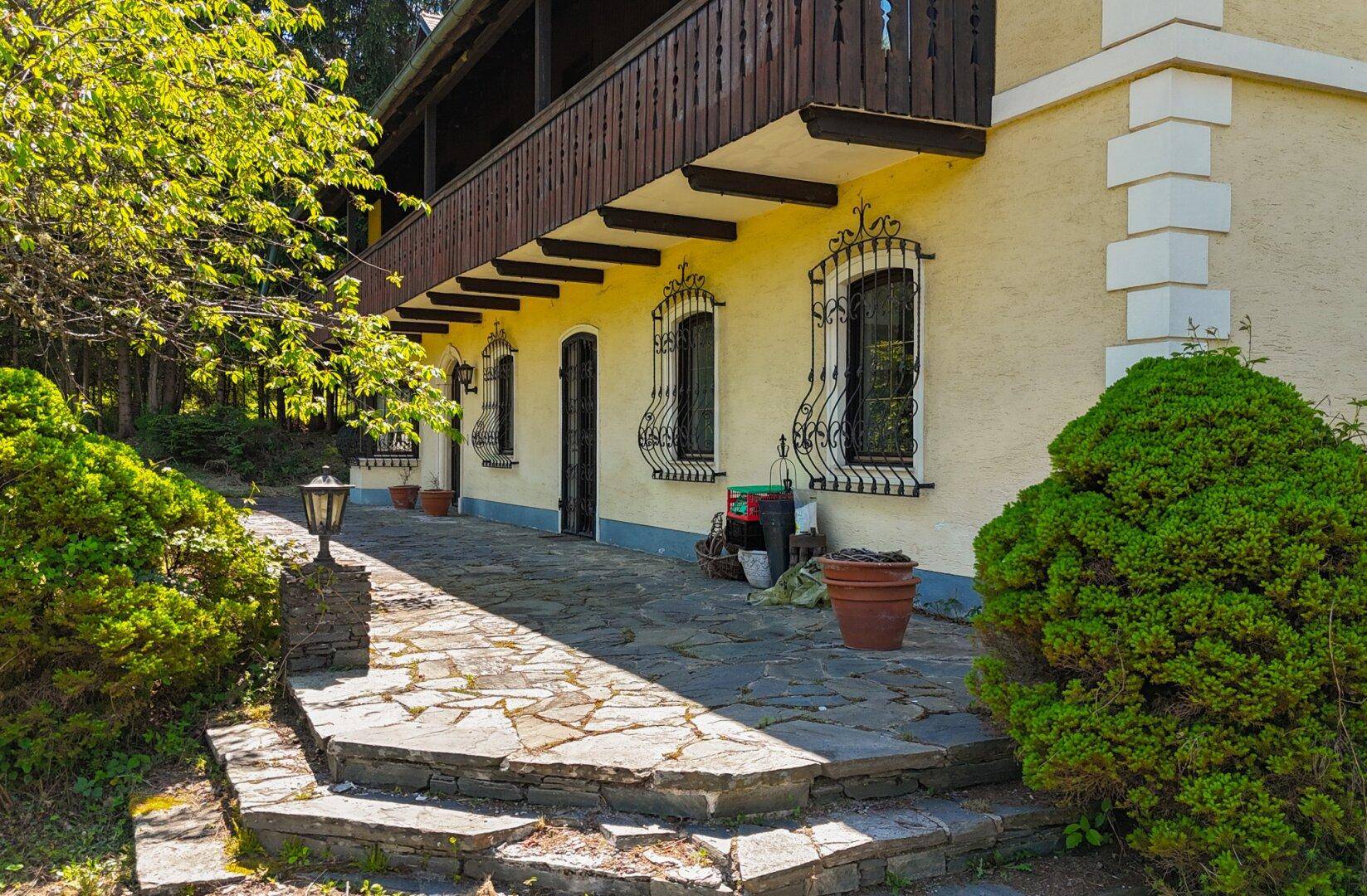 Gepflasterte Terrasse mit Natursteinplatten und Zugang zum Gartenbereich des Hauses.
