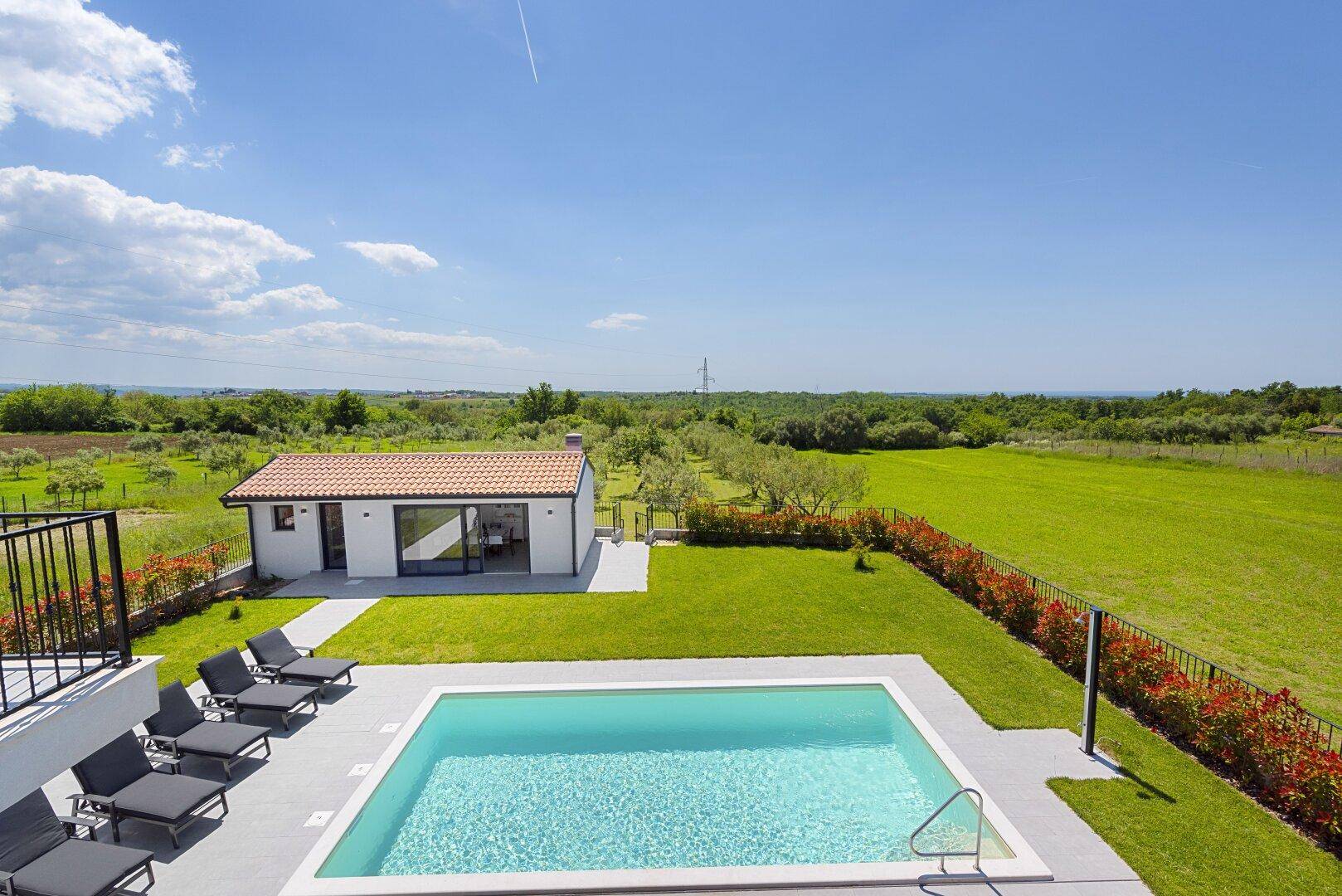 Weitläufiger Außenbereich mit großem Pool, Liegestühlen und Blick auf die umliegende Landschaft.