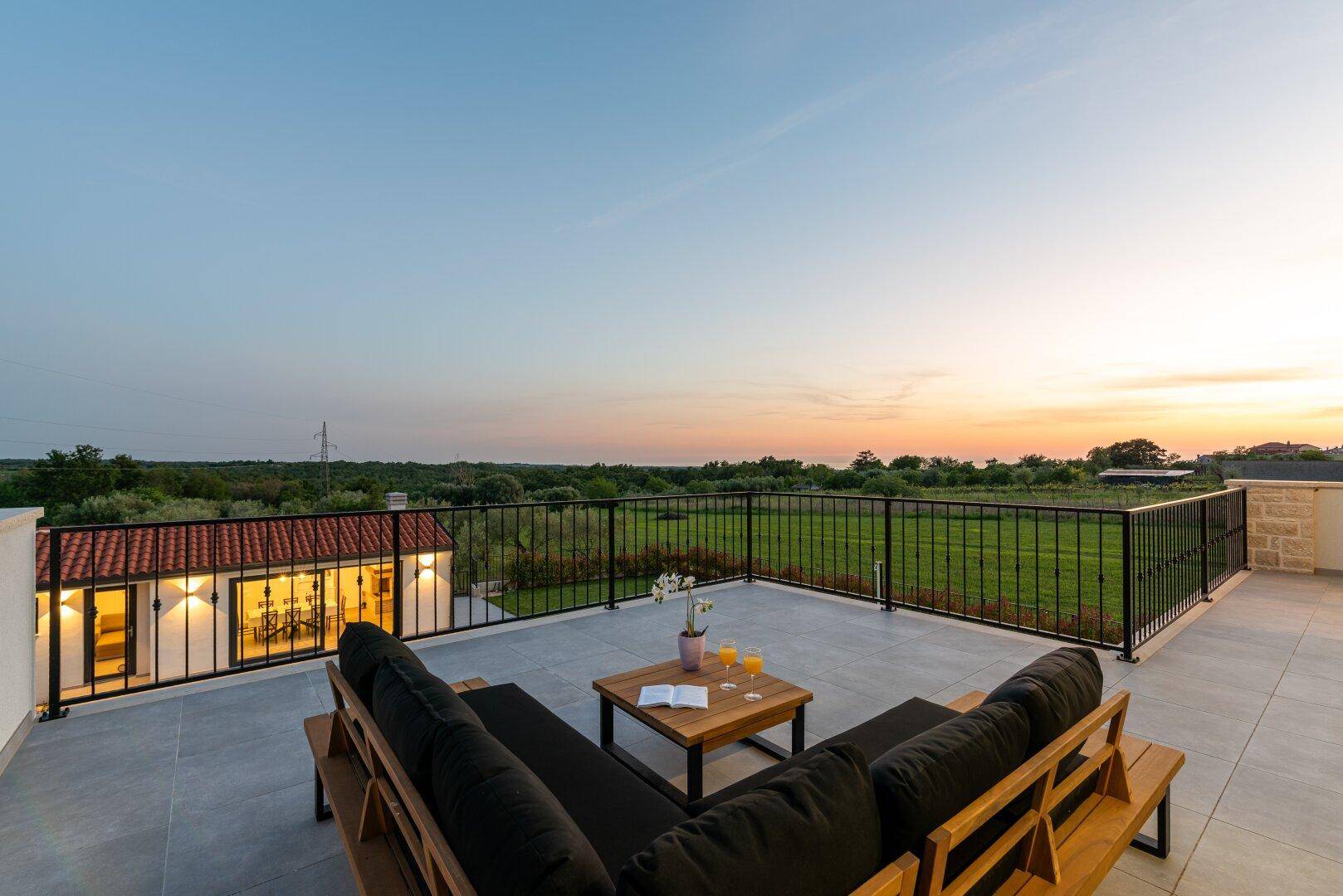 Stimmungsvolle Dachterrasse bei Sonnenuntergang mit bequemen Sitzgelegenheiten und weitem Ausblick.