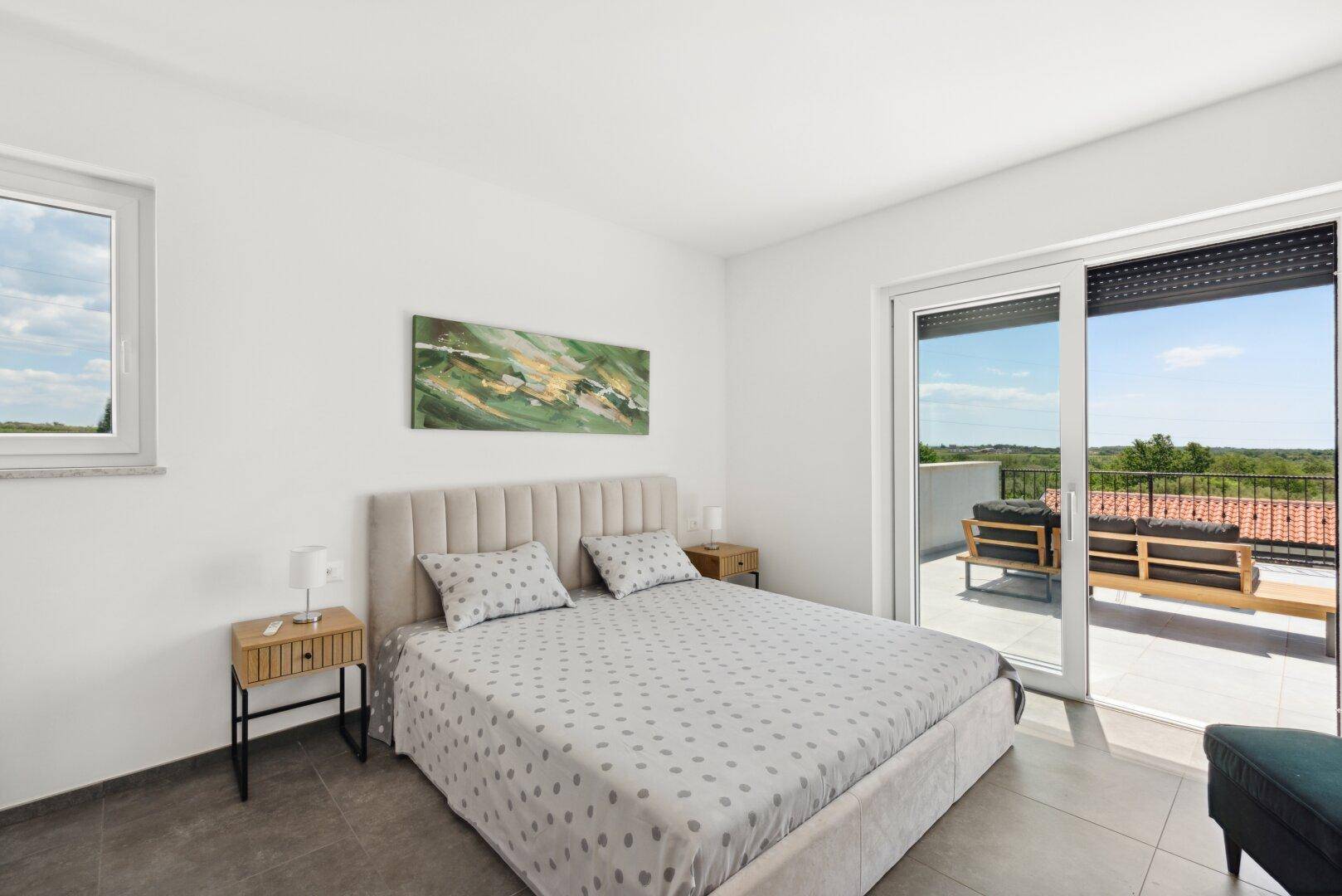 Gemütliches Schlafzimmer mit Doppelbett und direktem Zugang zu einer privaten Terrasse mit Sitzgelegenheiten.
