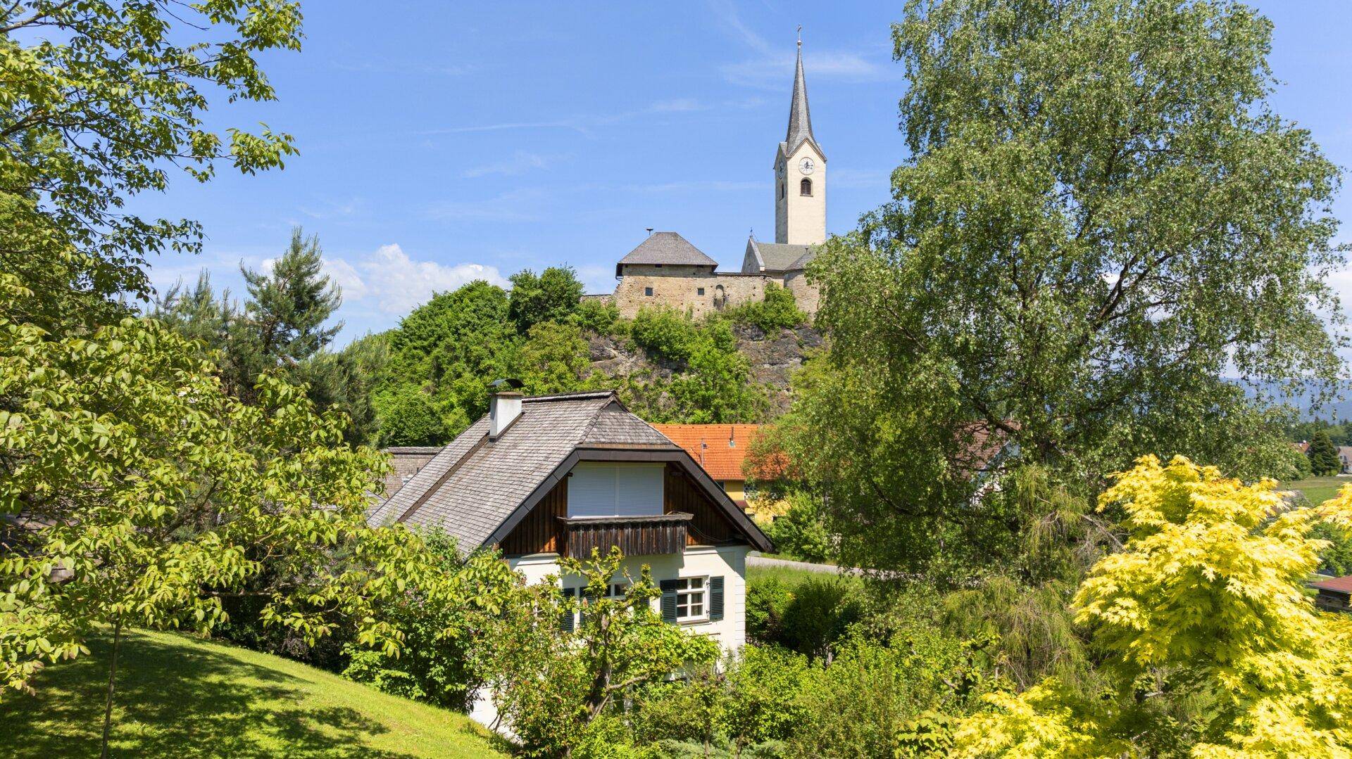 Traditionelles Haus in ländlicher Umgebung mit Blick auf eine historische Kirche und Burg.