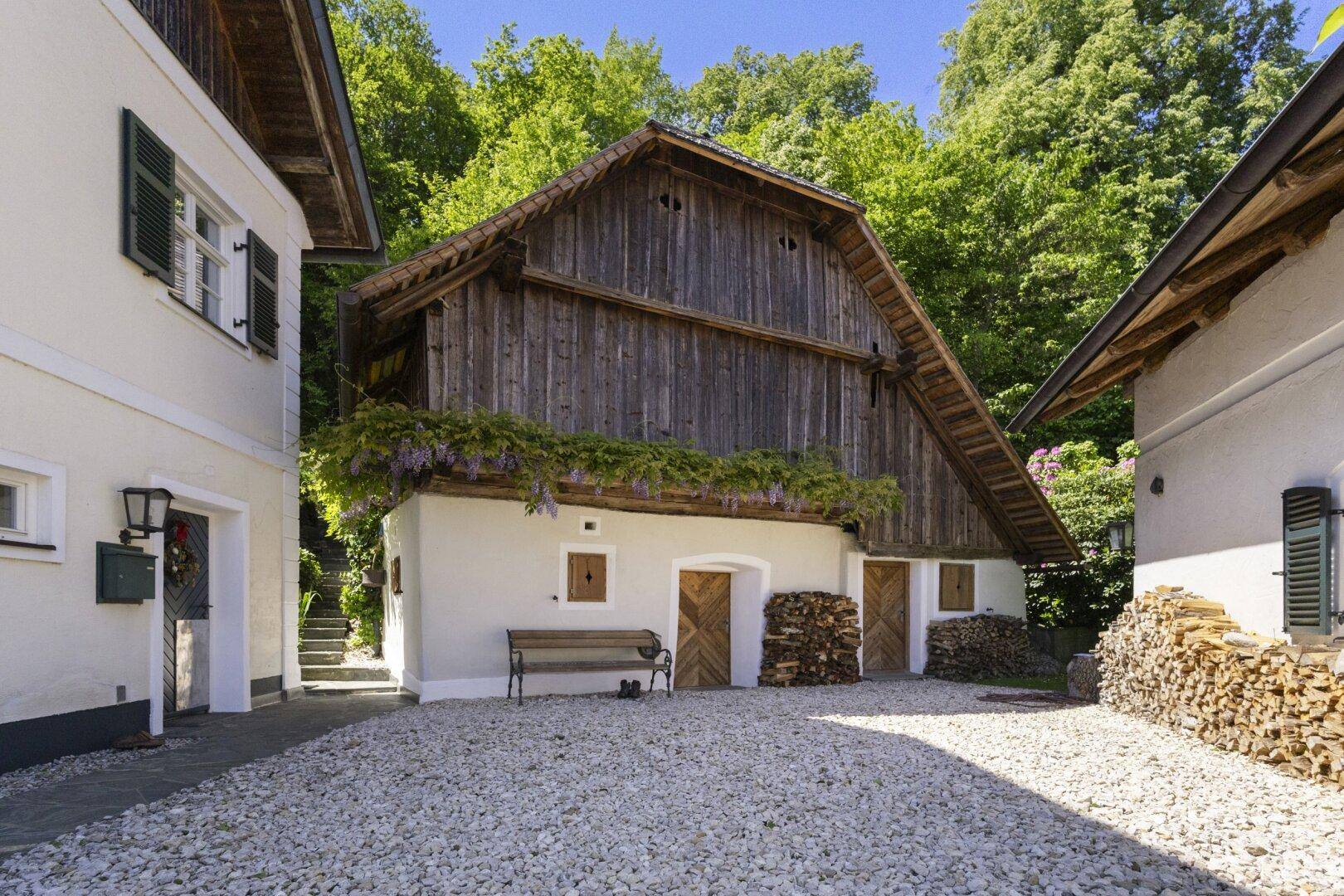 Rustikaler Innenhof zwischen Gebäuden mit gestapeltem Brennholz und traditioneller Holzfassade.