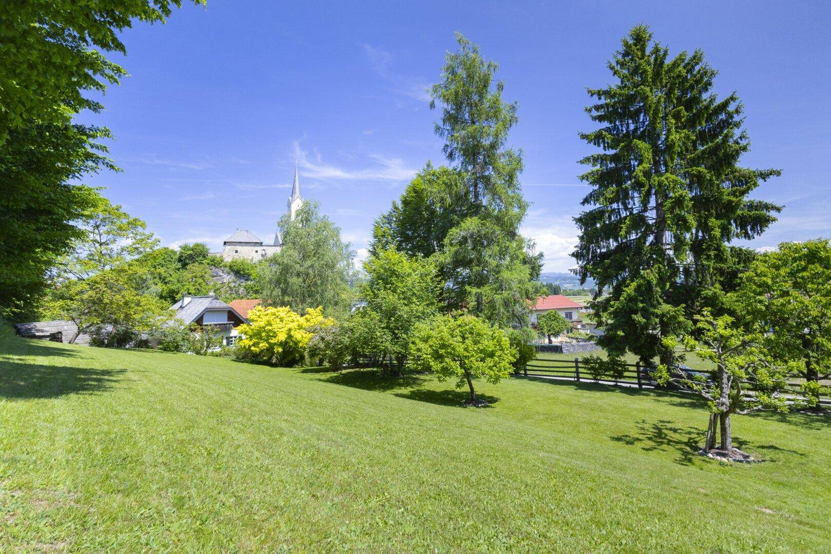 Großer, gepflegter Garten mit weitem Blick auf die Landschaft und eine Kirche in der Ferne.