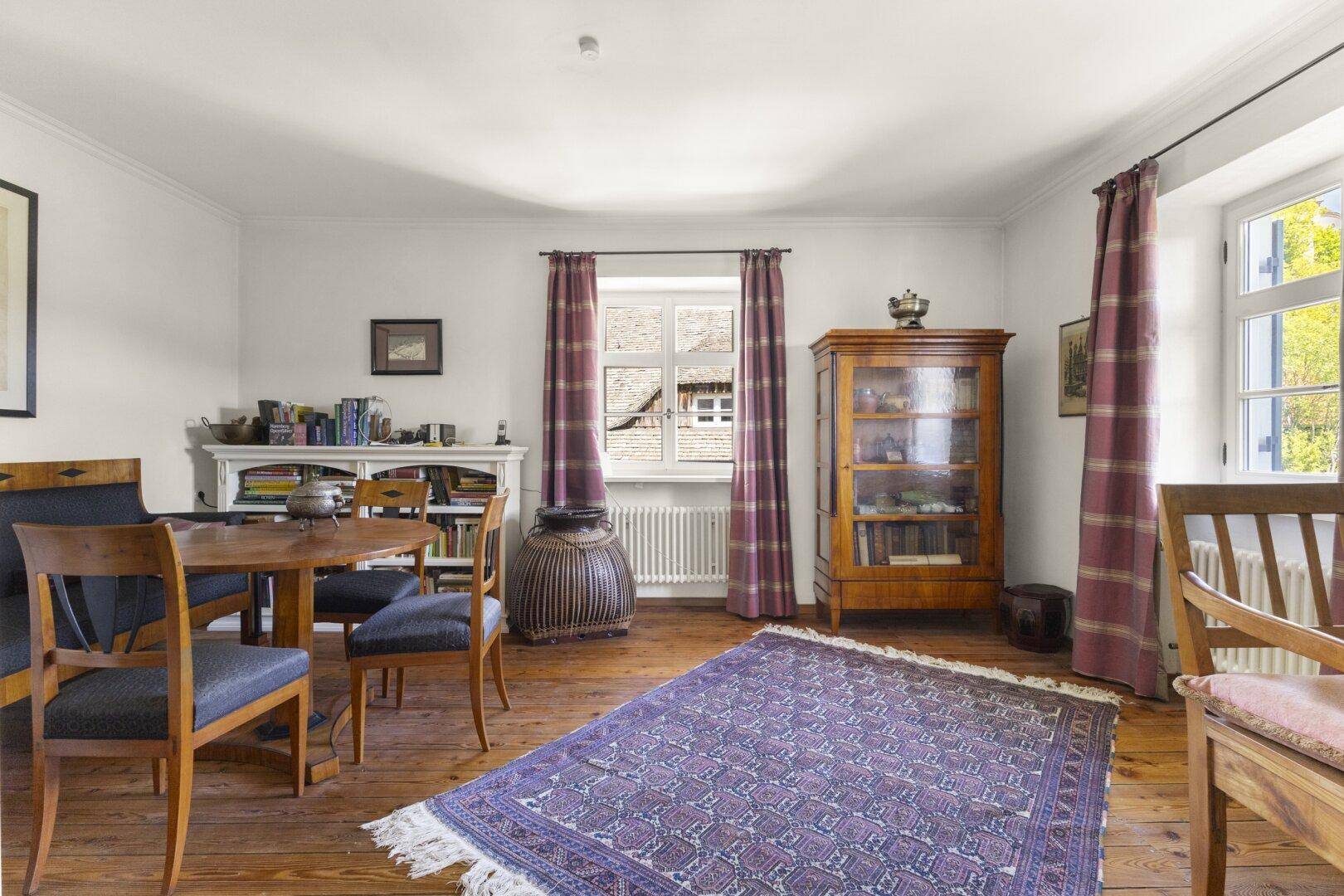 Traditionelles Wohnzimmer mit Holzdielenboden, antiken Möbeln und einem Teppich.