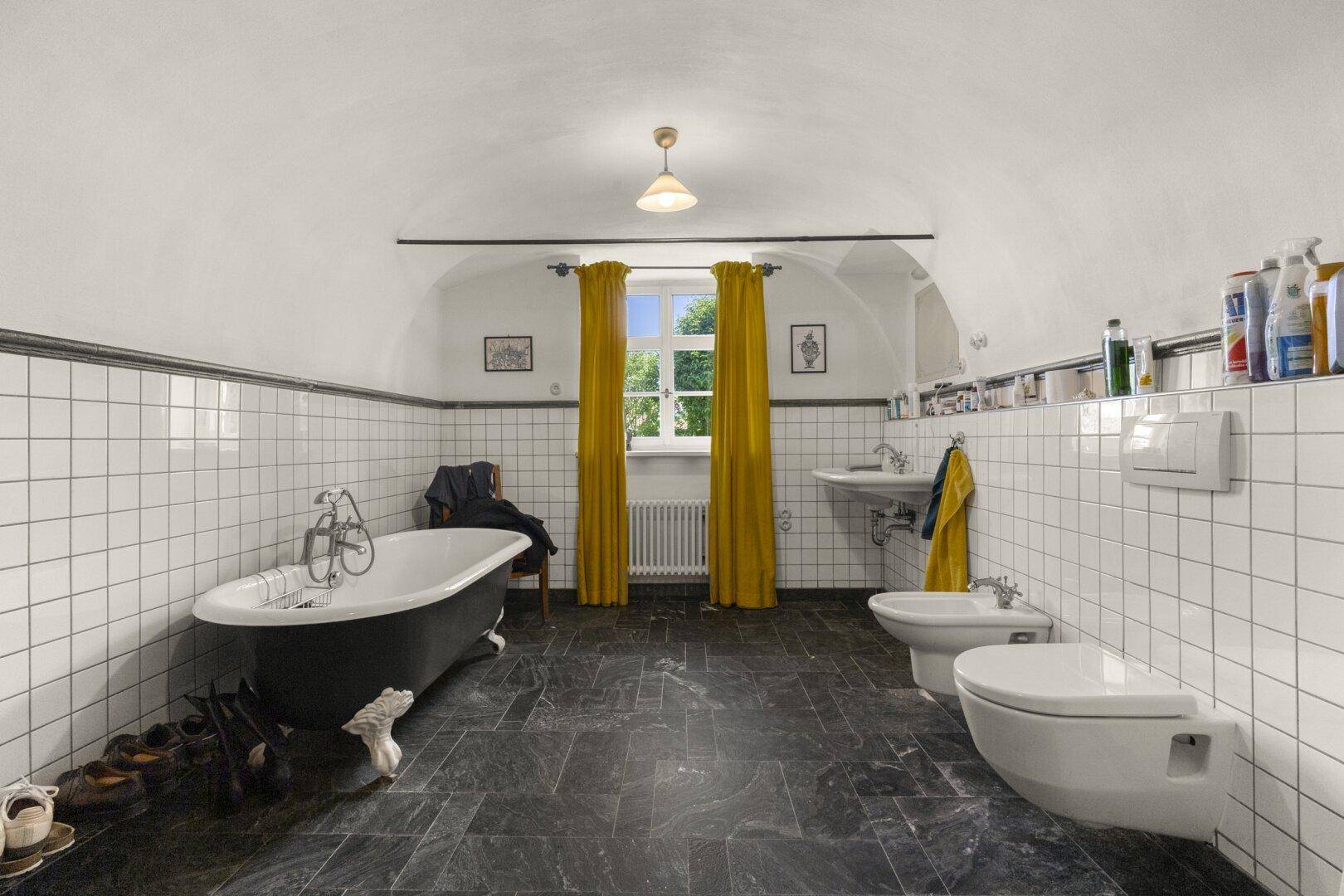 Geräumiges Badezimmer mit freistehender Badewanne, Bidet, Toilette und gewölbter Decke.