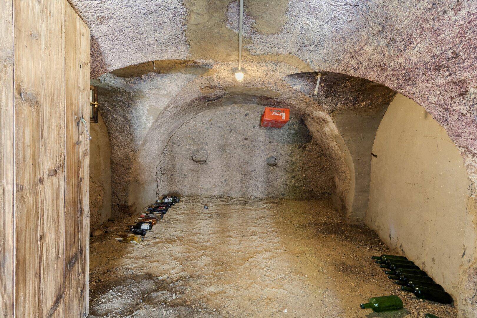 Historischer Weinkeller mit gewölbten Decken und Flaschenlagerung, ideal für Weinliebhaber.