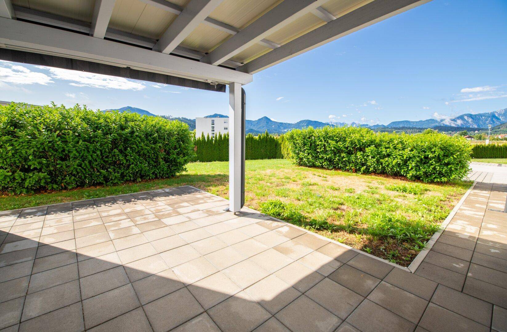 Überdachte Terrasse mit gepflastertem Boden und Blick auf die umliegende Berglandschaft.