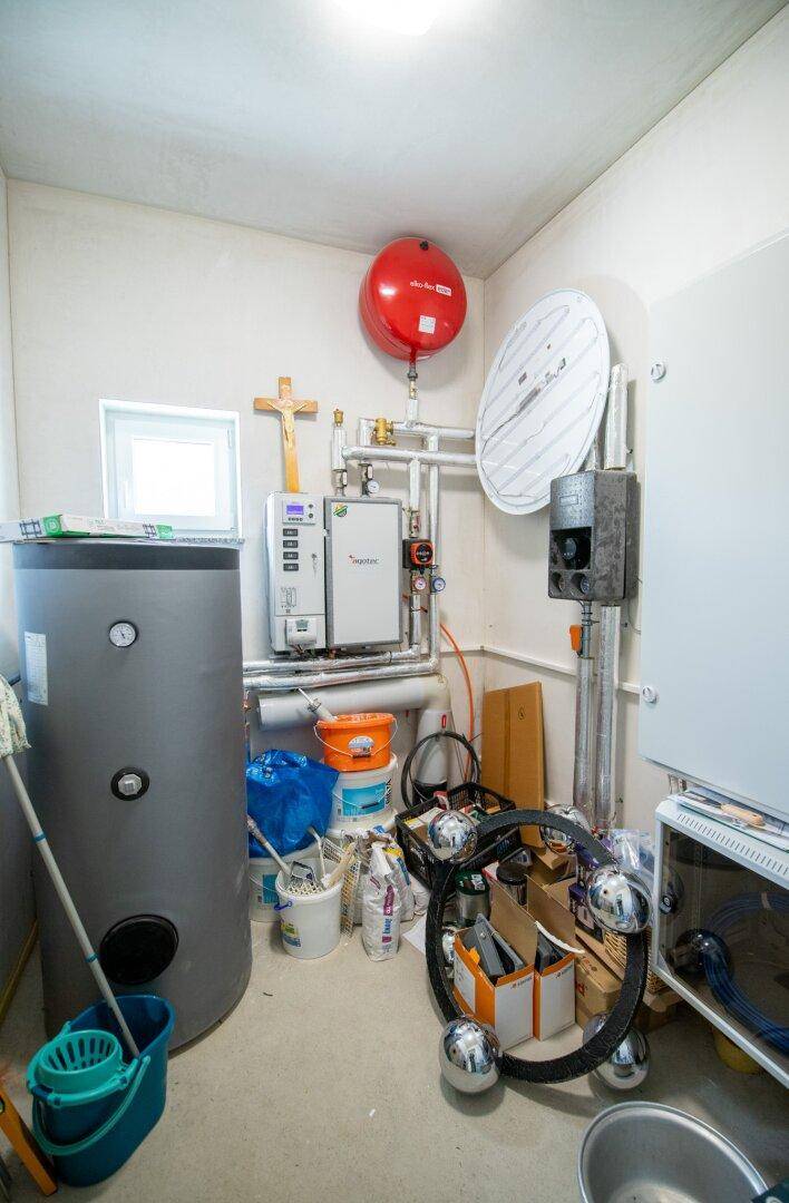 Technikraum mit Warmwasserspeicher, Heizungsanlage und verschiedenen Installationen.