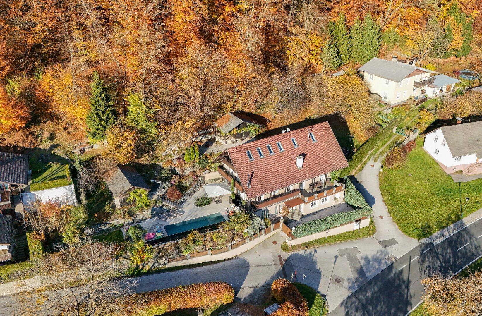 Weitläufige Luftaufnahme des Hauses mit Pool und der herbstlichen Landschaft im Hintergrund.