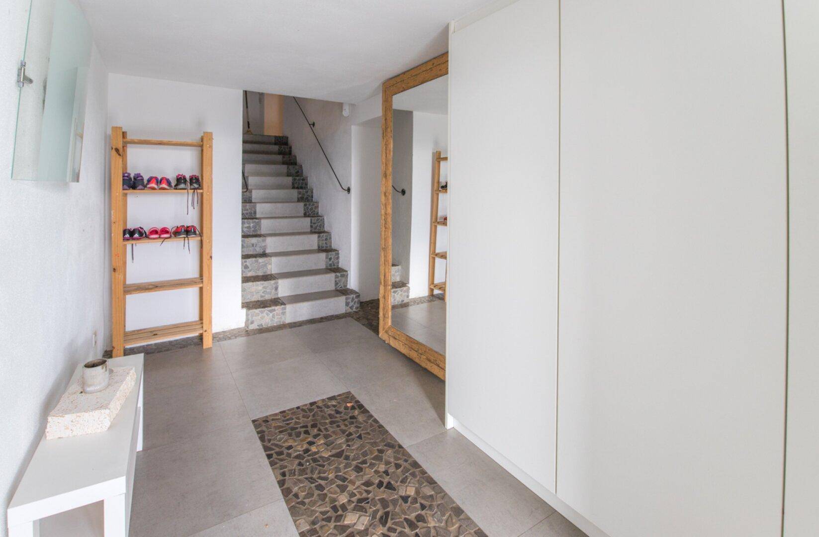 Heller Flur mit großem Spiegel, weißen Einbauschränken und Treppe zum Obergeschoss.
