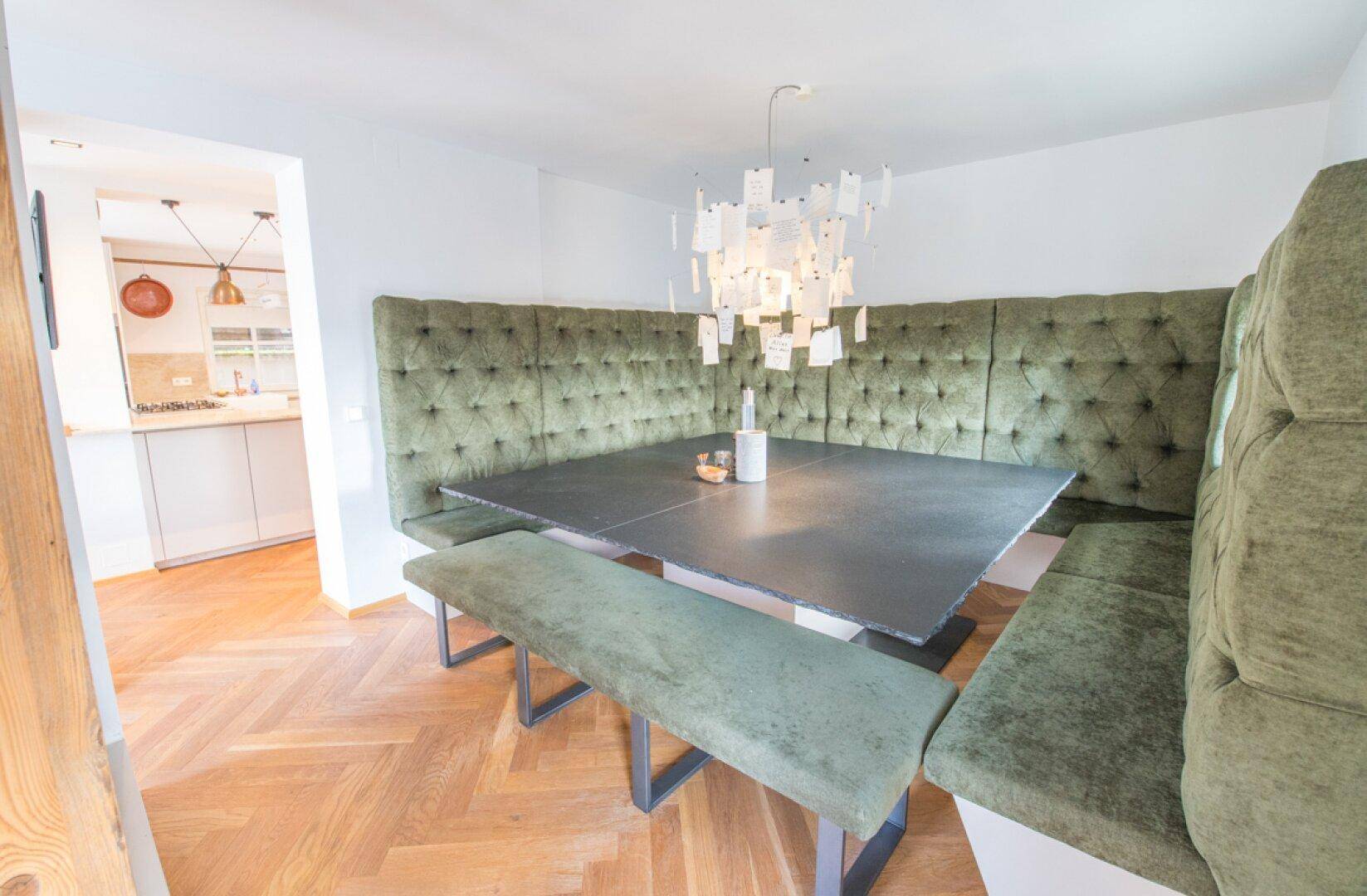 Gemütlicher Essbereich mit gepolsterter Eckbank, großem Tisch und Holzboden.