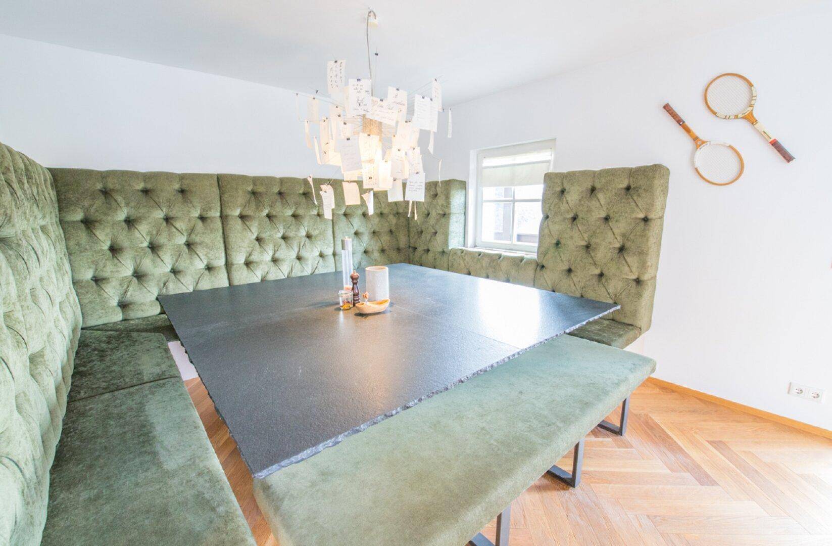 Heller Essbereich mit grüner Eckbank, modernem Esstisch und Fenster für Tageslicht.
