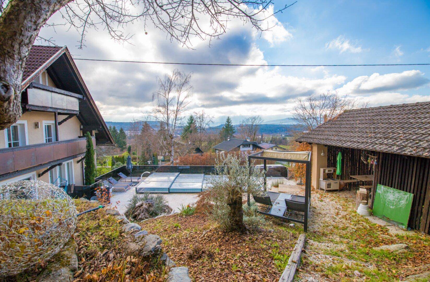 Gartenbereich mit Blick auf das Haus, den Pool und die umliegende hügelige Landschaft.