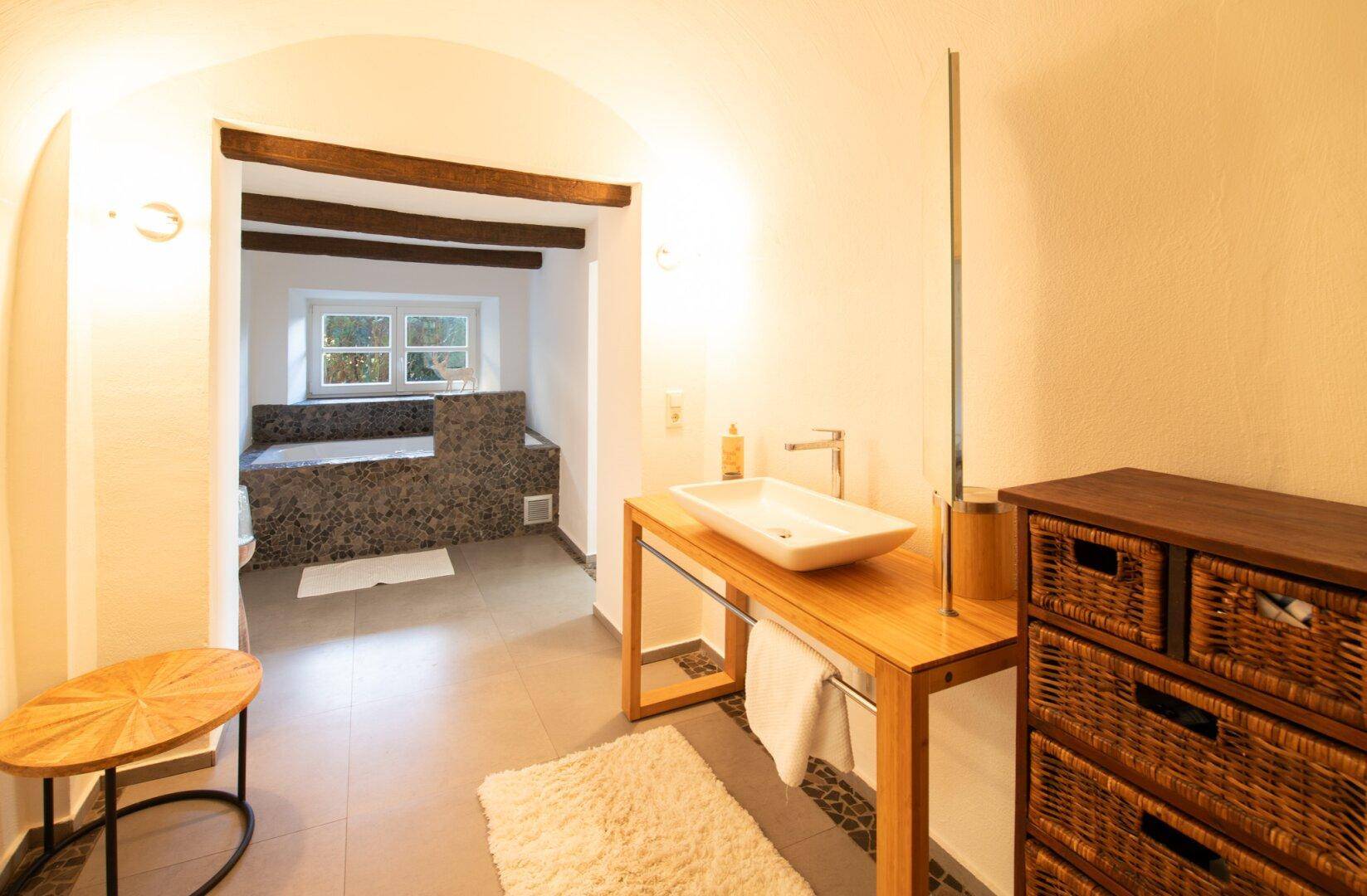 Rustikales Badezimmer mit freistehendem Waschbecken, Holzelementen und Badewanne am Fenster.
