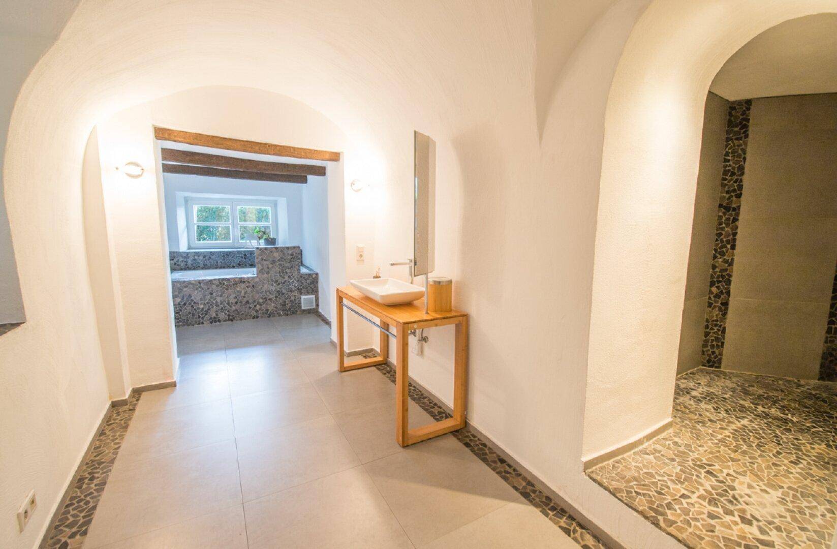 Geräumiges Badezimmer mit gewölbten Decken, einem modernen Waschbecken und einem eingebauten Whirlpool.
