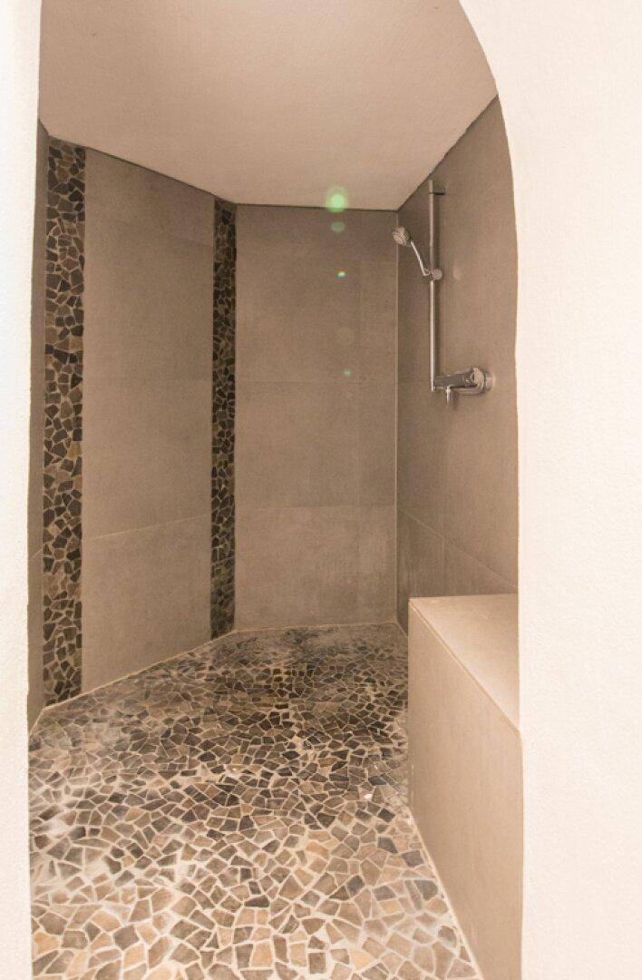 Geräumiger Duschbereich mit Mosaikboden und modernen Fliesen an den Wänden.