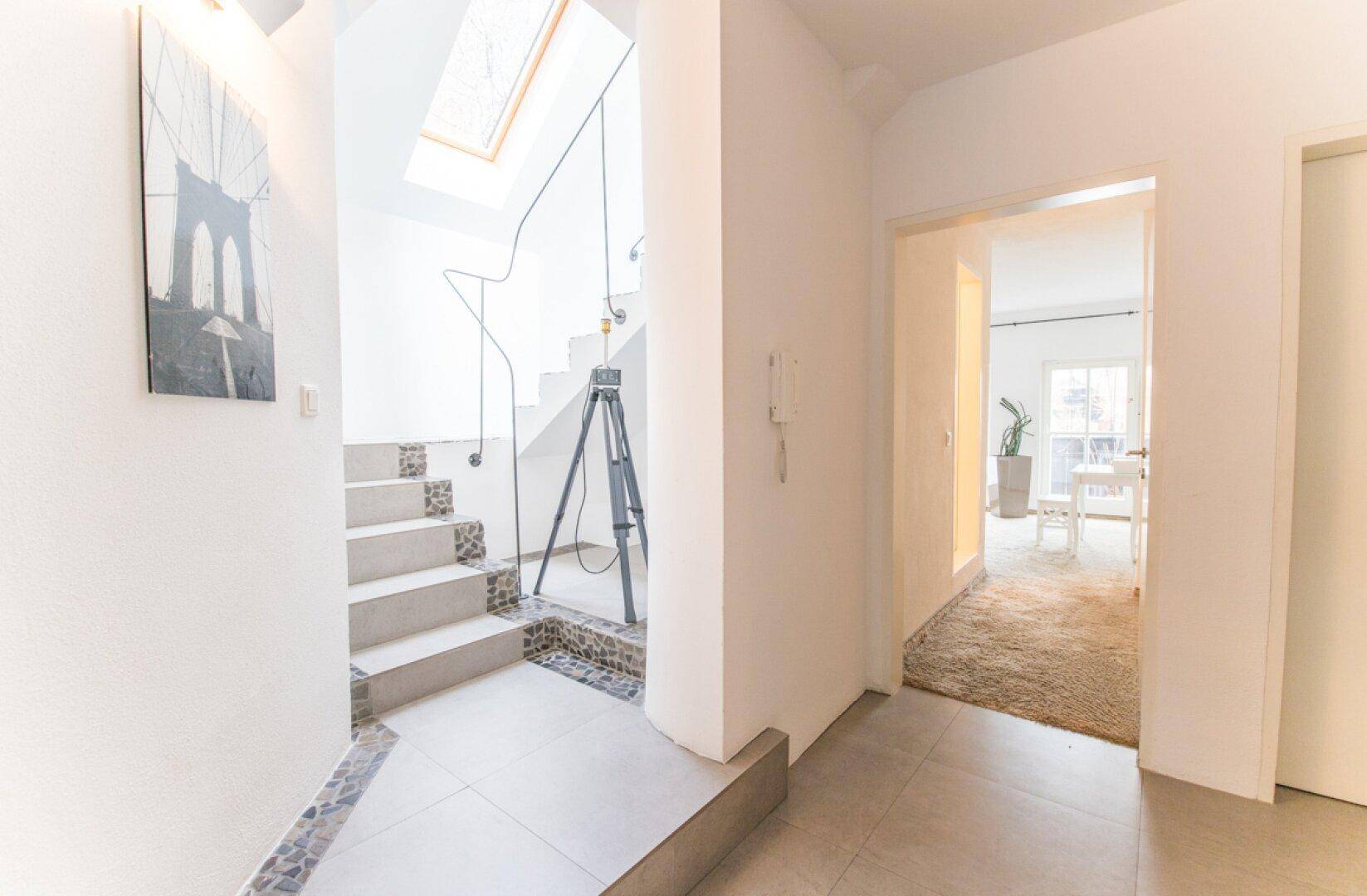 Heller Flur mit Treppe, Oberlicht und Blick in einen angrenzenden Wohnbereich.