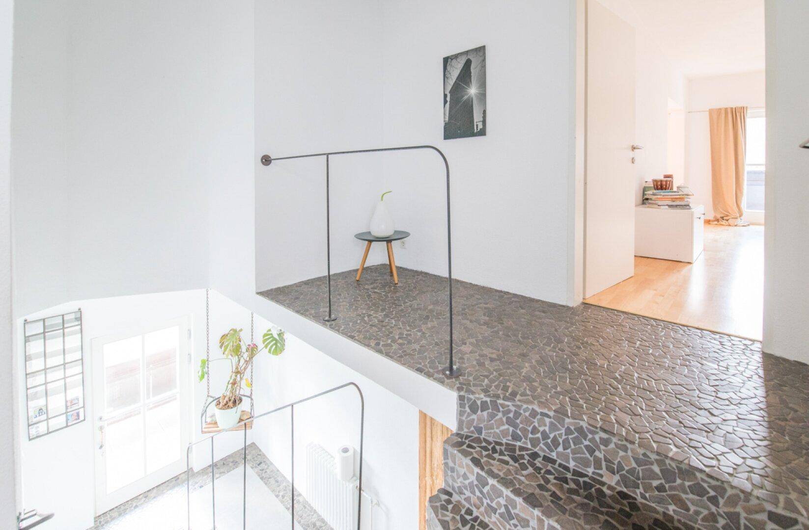 Heller Treppenabsatz mit Geländer und Blick auf die untere Etage.