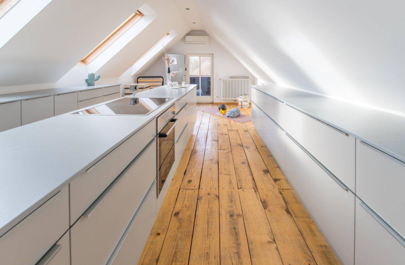 Moderne Küche im Dachgeschoss mit schrägen Decken, Oberlichtern und Holzdielenboden.