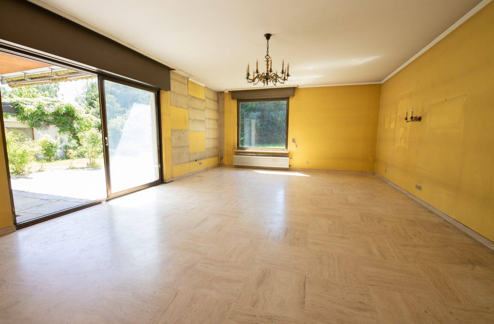 Geräumiges Wohnzimmer mit gelben Wänden, Marmorboden und Zugang zur Terrasse.