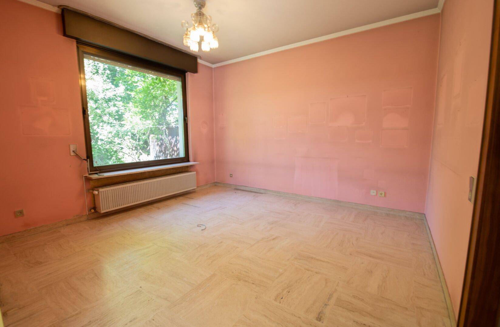 Schlafzimmer mit rosa Wänden, großem Fenster und hellem Marmorboden.