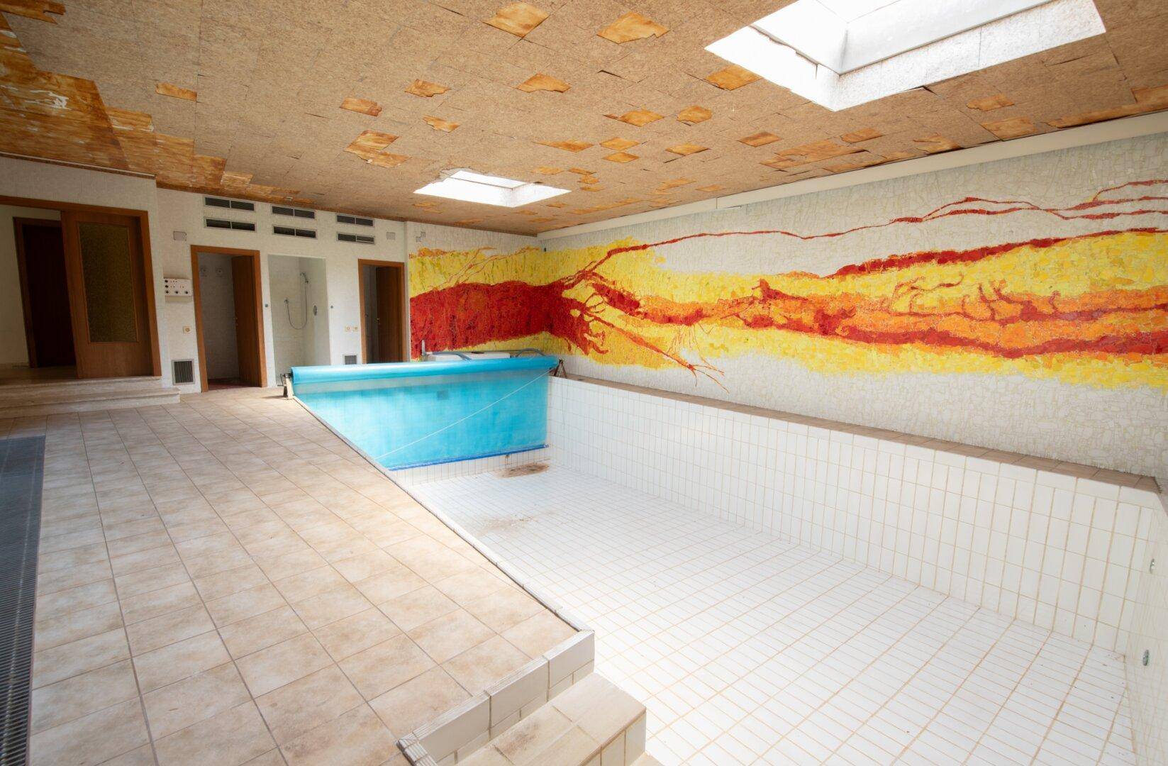 Großer Innenpoolbereich mit farbenfrohem Mosaik, Oberlichtern und gefliestem Boden.