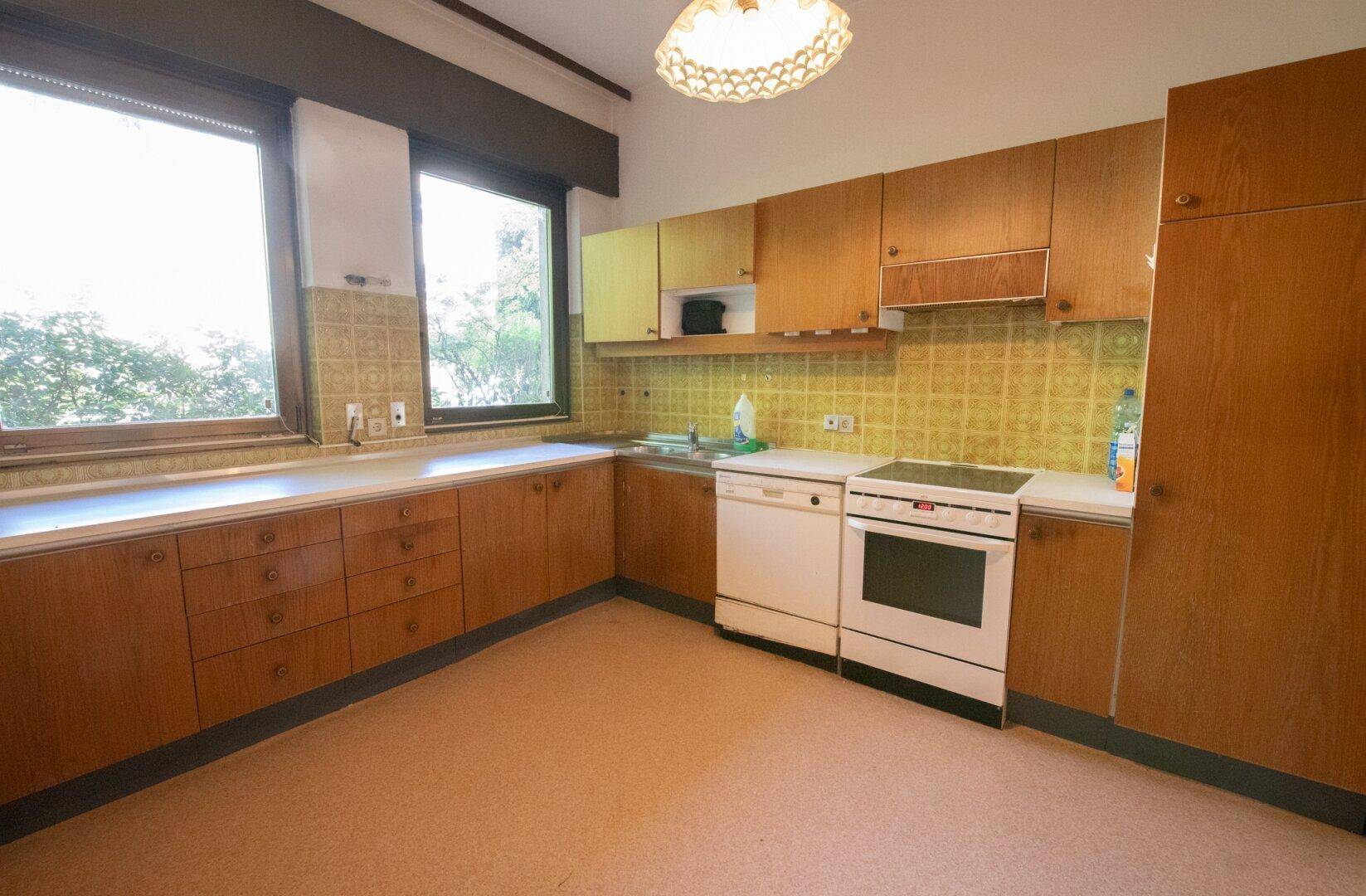 Traditionelle Küche mit Holzschränken, älteren Geräten und gefliestem Spritzschutz.