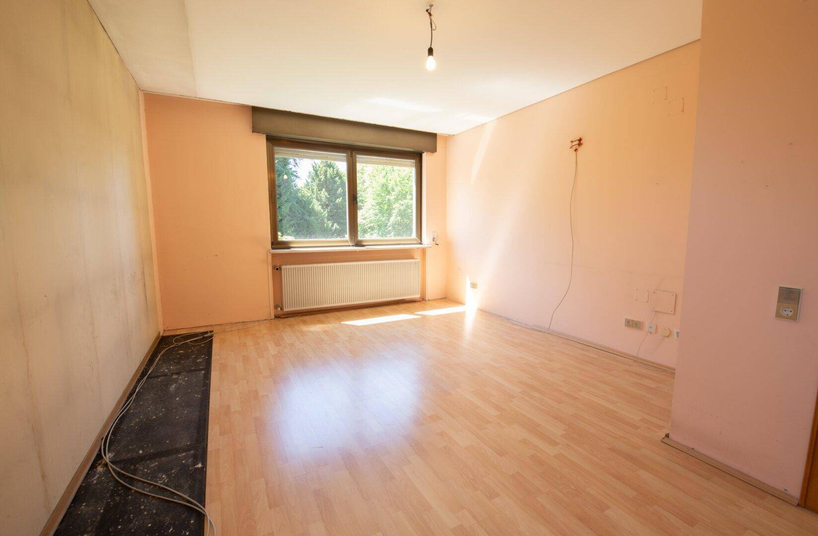 Zimmer mit pfirsichfarbenen Wänden und teilweise entferntem Laminatboden.