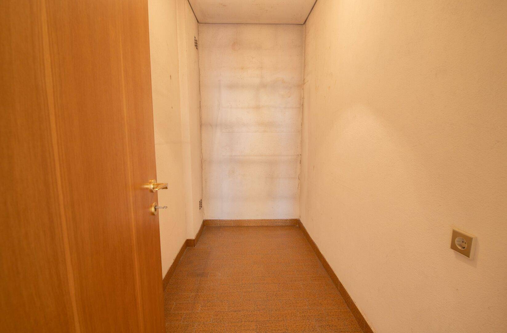 Kleiner Abstellraum mit einfacher Ausstattung und Holztür.