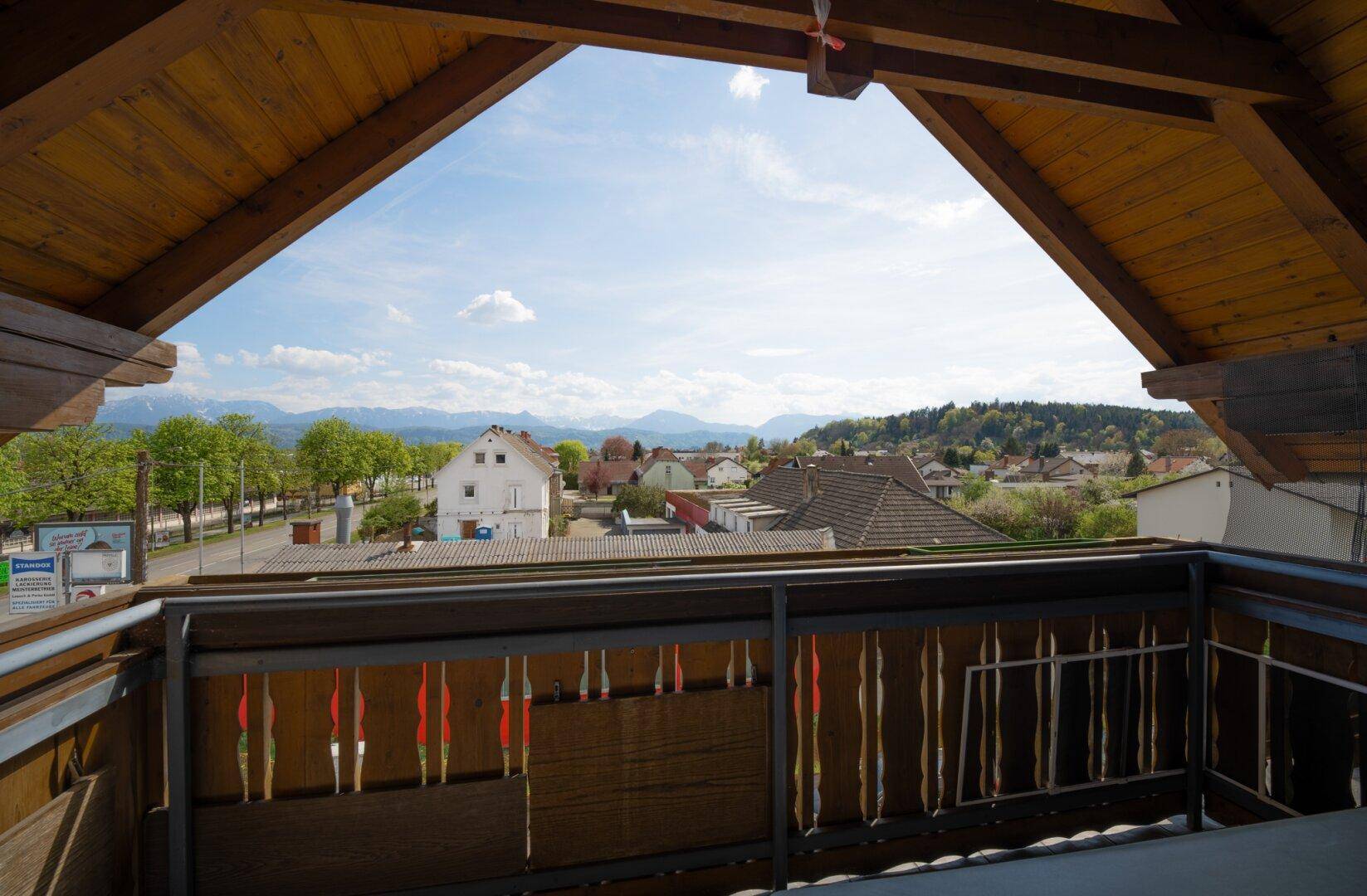 Balkon mit Holzboden und Geländer bietet einen weiten Blick auf die umliegende Landschaft und Berge.