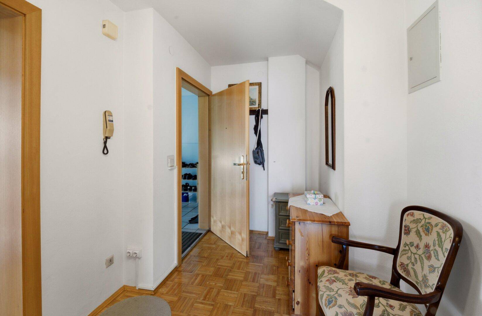 Heller Flur mit Parkettboden, Garderobe und einem kleinen Schrank.