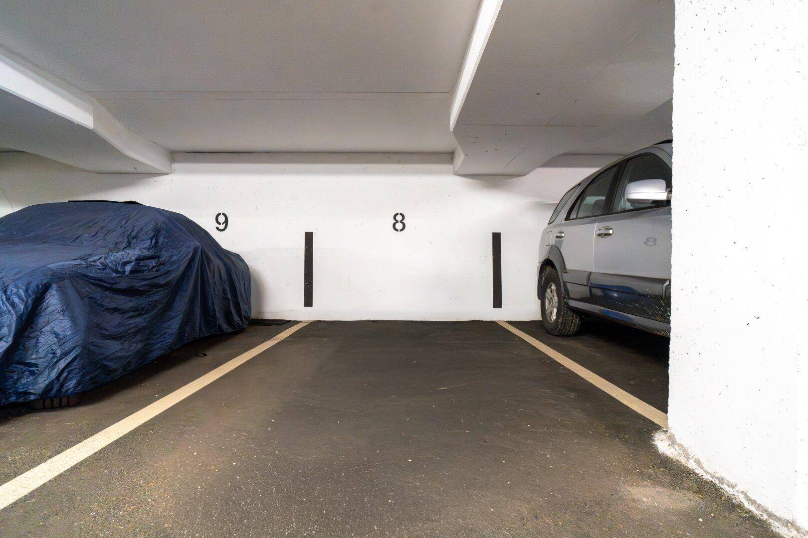 Tiefgaragenstellplätze für Fahrzeuge, nummeriert und gut beleuchtet, mit einem geparkten Auto.