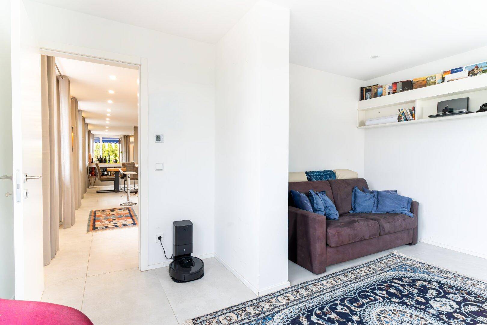 Gemütlicher Wohnbereich mit Sofa, Teppich und Bücherregal, offen zum Hauptwohnraum.