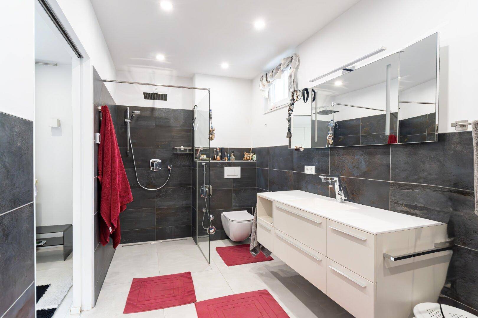 Modernes Badezimmer mit ebenerdiger Dusche, Wand-WC und großem Waschtisch, stilvoll gefliest.