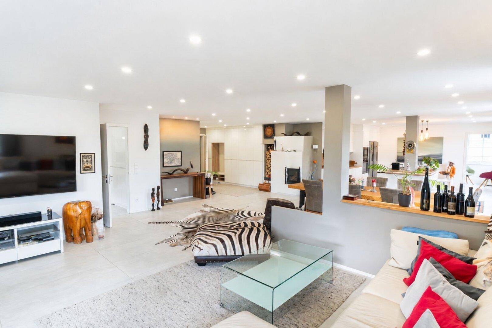 Gemütlicher Wohnbereich mit Kamin, großem Sofa und modernen Fliesen, dekoriert mit Zebra-Teppichen.