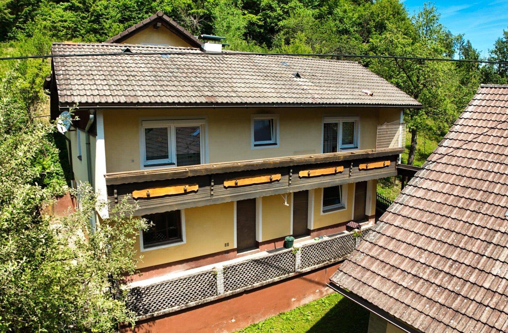Mehrstöckiges Wohnhaus mit Balkonen und traditioneller Architektur, umgeben von Bäumen.