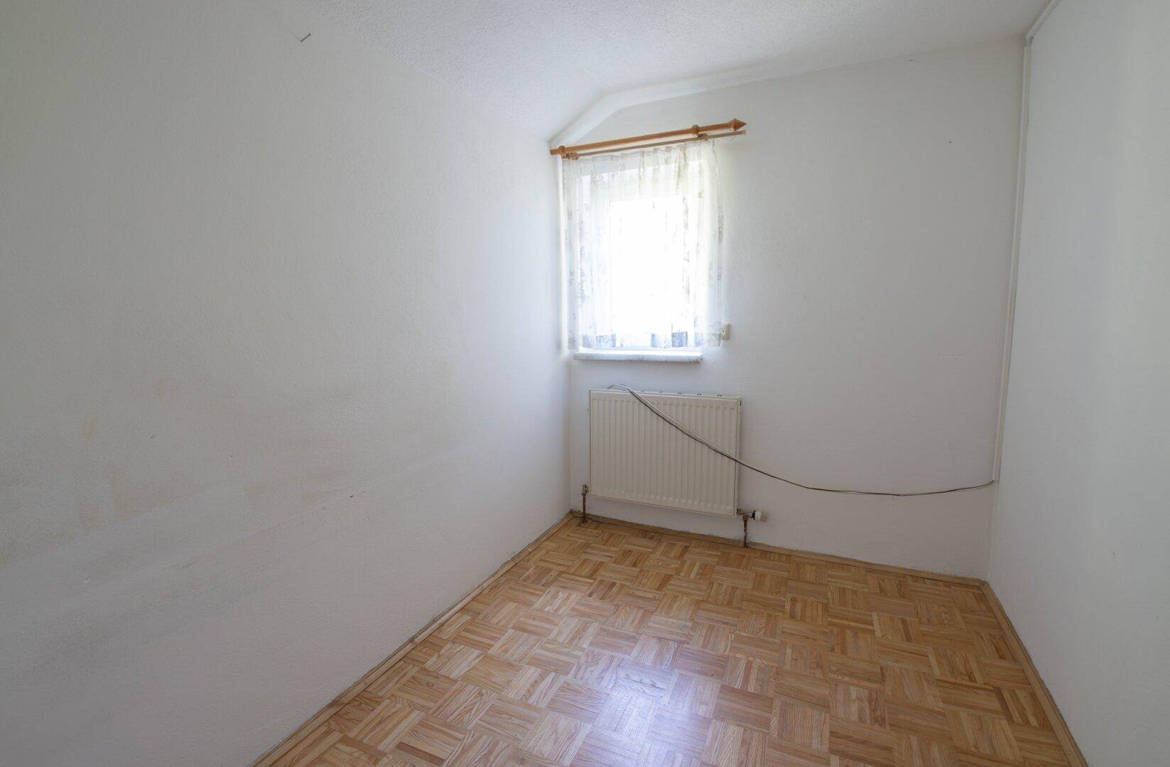 Kleiner, heller Raum mit Parkettboden und einem Fenster, ideal als Kinder- oder Arbeitszimmer.