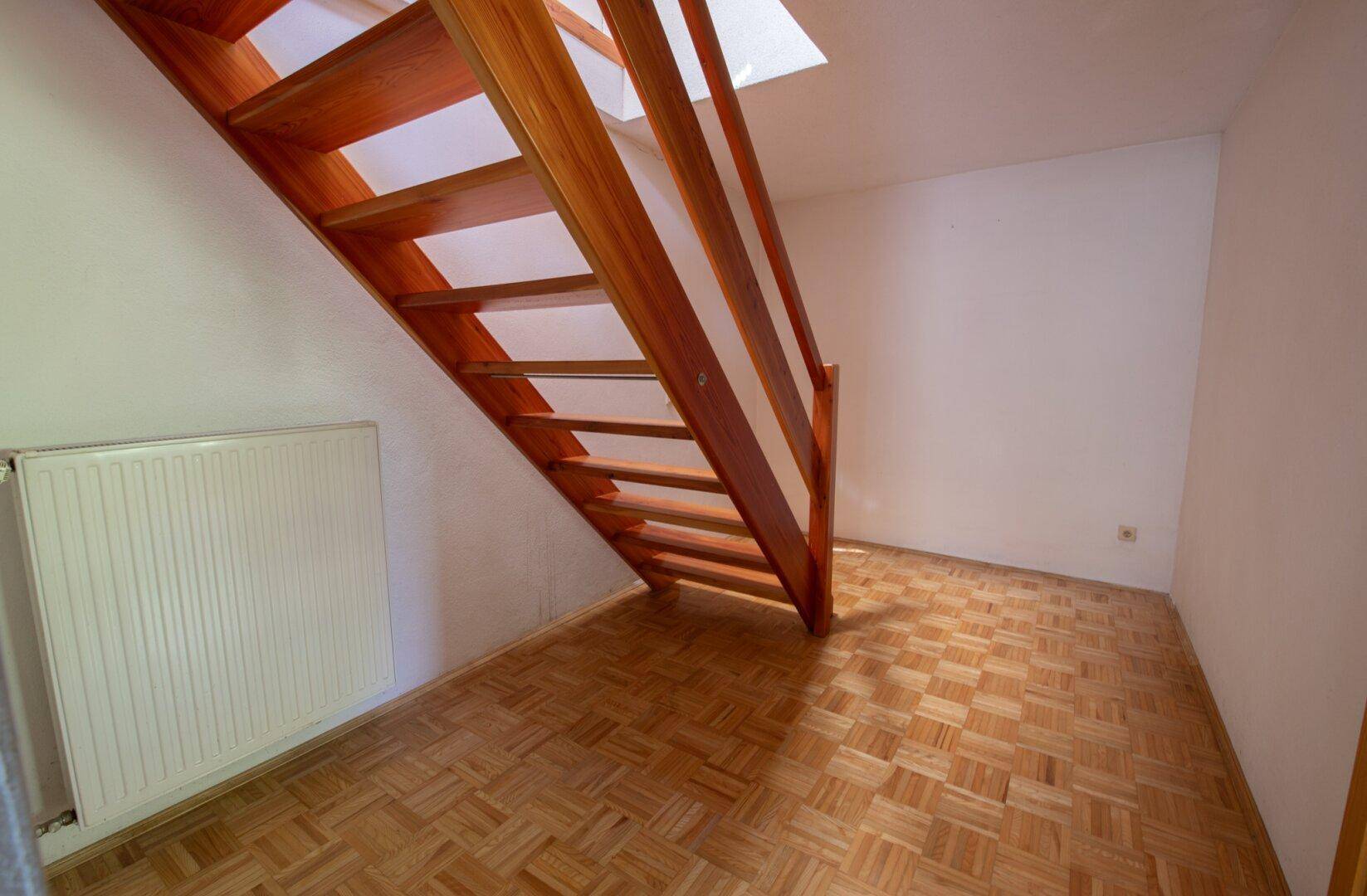 Heller Flur mit Holztreppe und Parkettboden, führt ins obere Stockwerk.