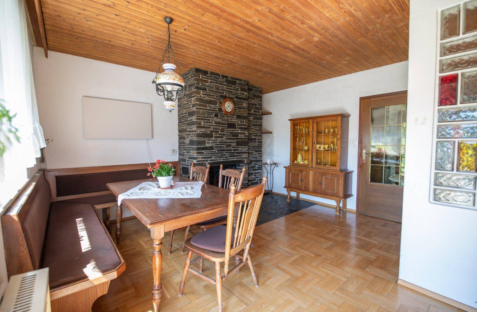 Essbereich mit Kamin, Holztisch und traditioneller Einrichtung unter Holzdecke.