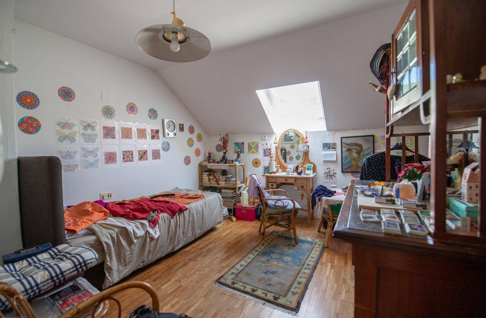Kinderzimmer im Dachgeschoss mit Bett, Schreibtisch und Dachfenster.