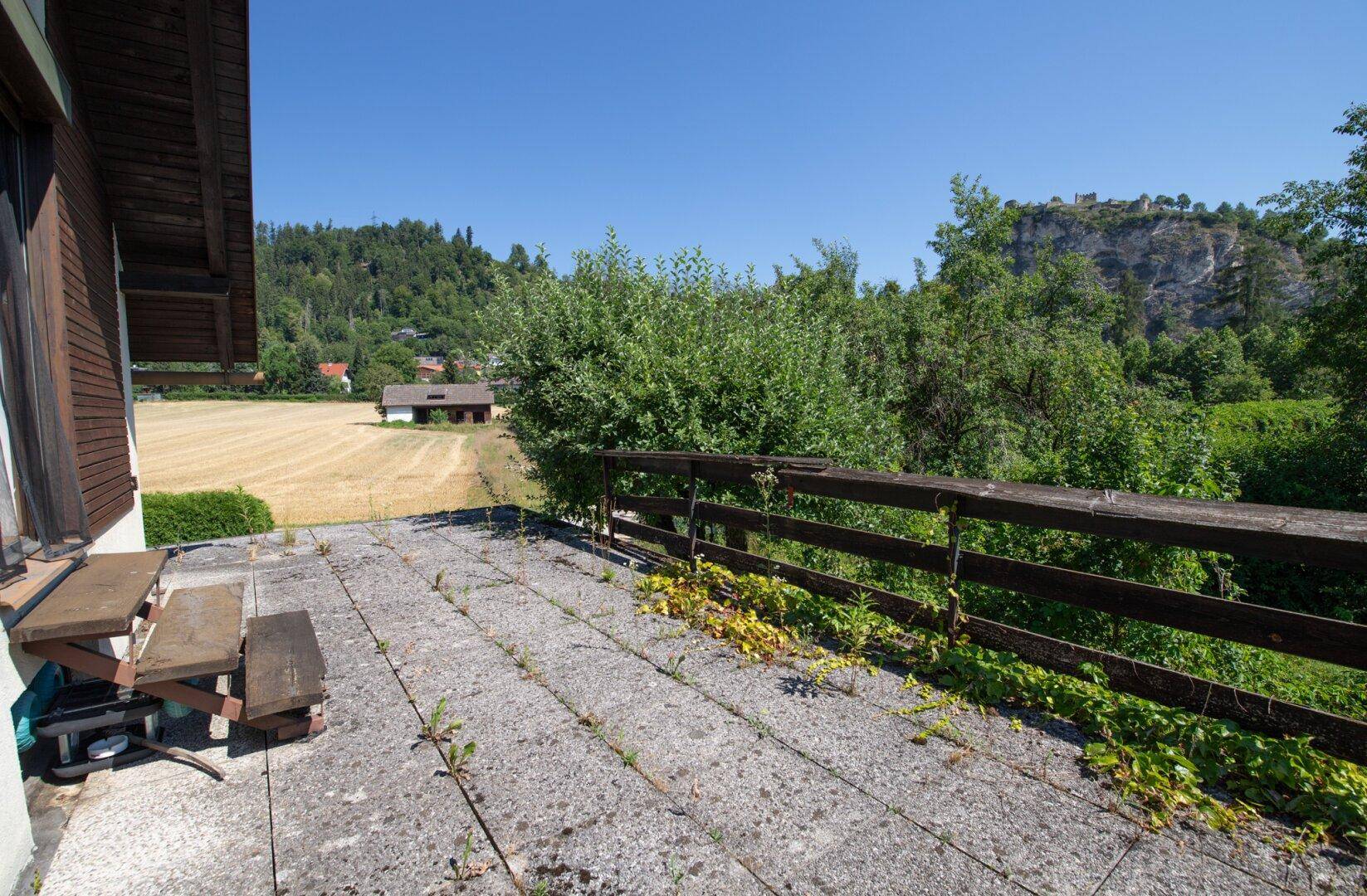 Große, ungenutzte Betonterrasse mit Blick auf Felder und Berge.