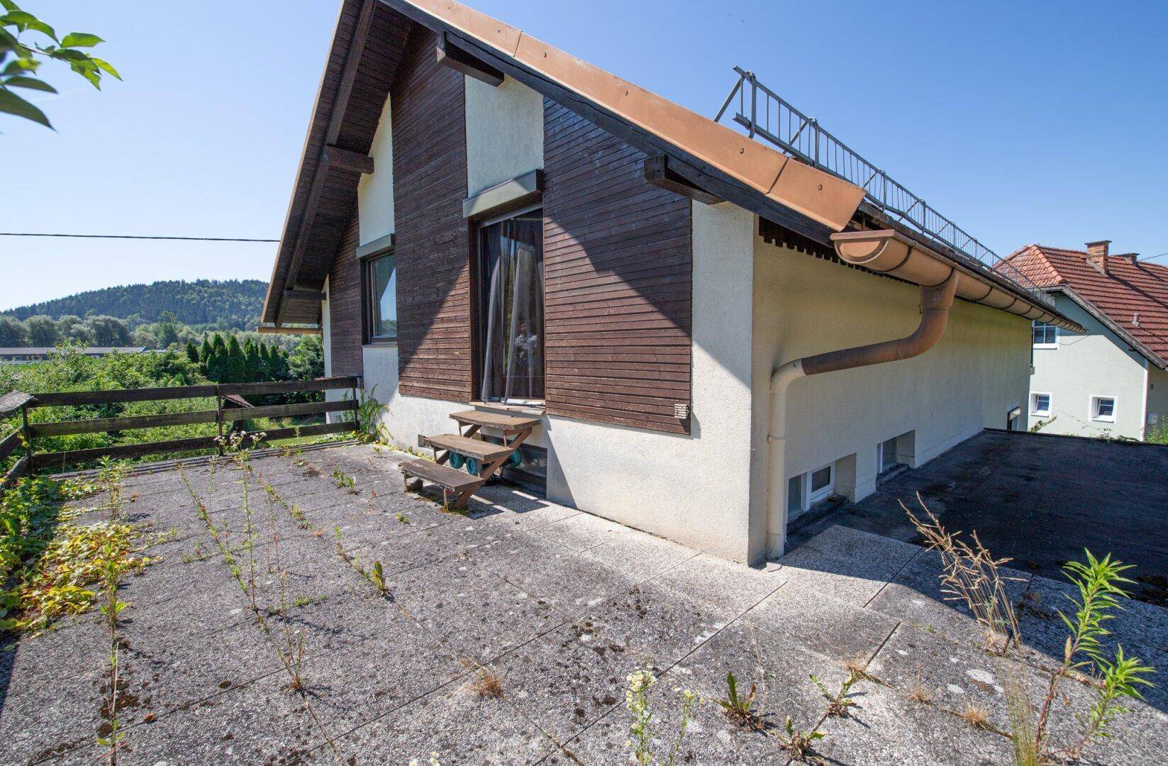 Weitläufige Betonterrasse am Haus mit Zugang zum Gartenbereich.