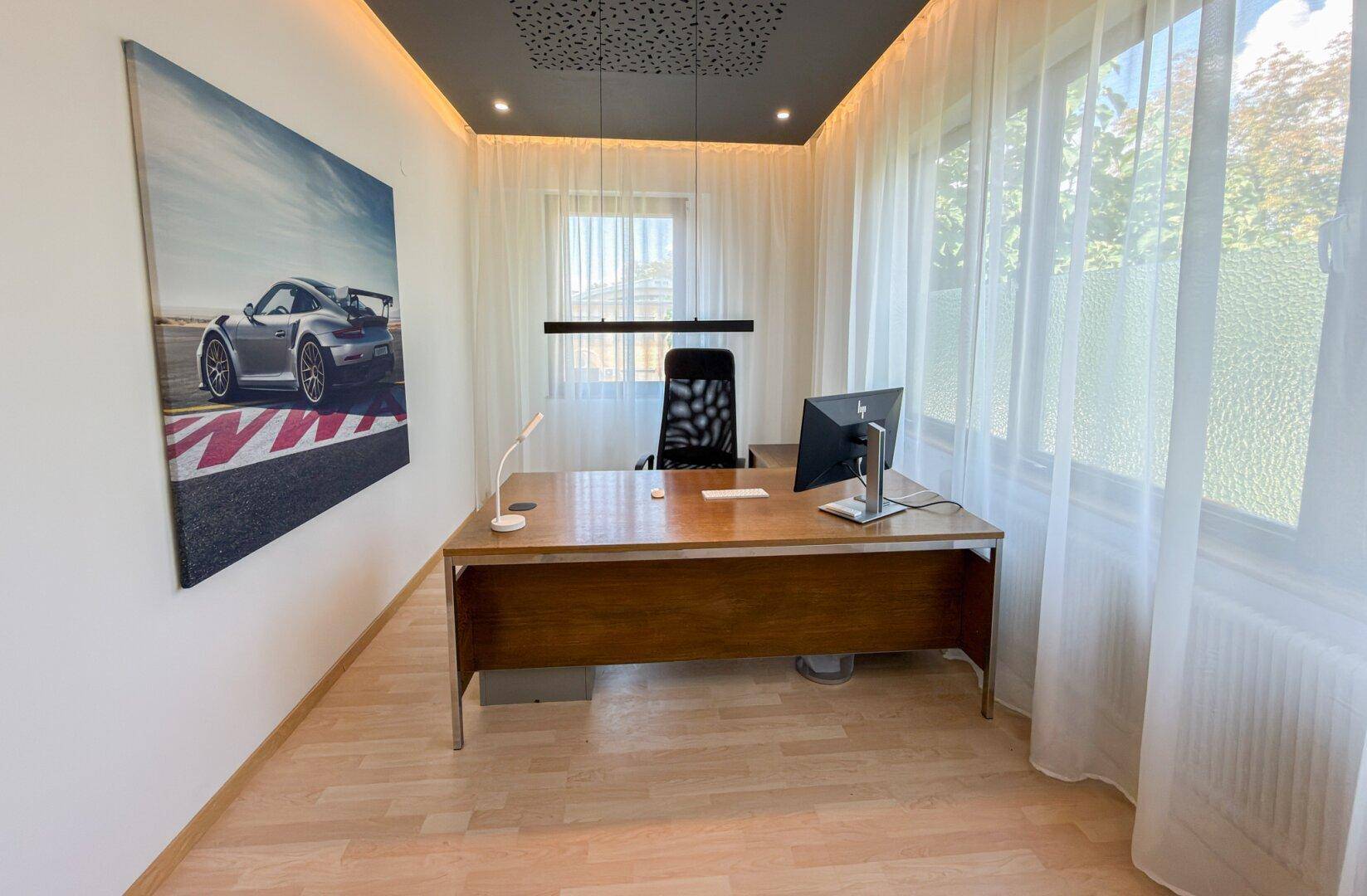 Geräumiges Büro mit dunklem Holztisch, Bürostuhl und einem großen Kunstwerk an der Wand.