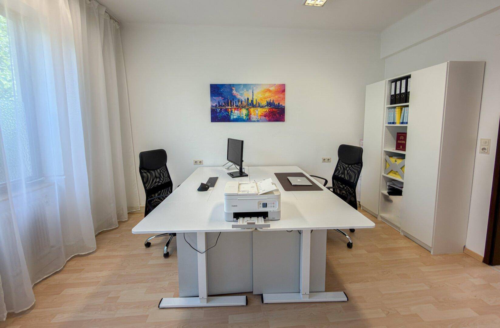 Helles Doppelbüro mit zwei modernen Schreibtischen, Bürostühlen und einem weißen Bücherregal.