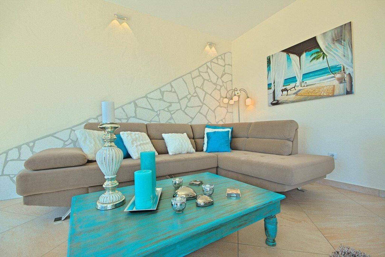 Gemütliche Sitzecke im Wohnzimmer mit beigefarbener Eckcouch und türkisfarbenem Couchtisch.