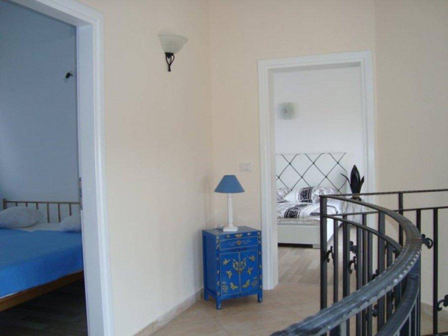 Heller Flur im Obergeschoss mit dekorativem blauen Schrank und Zugang zu den Schlafzimmern.